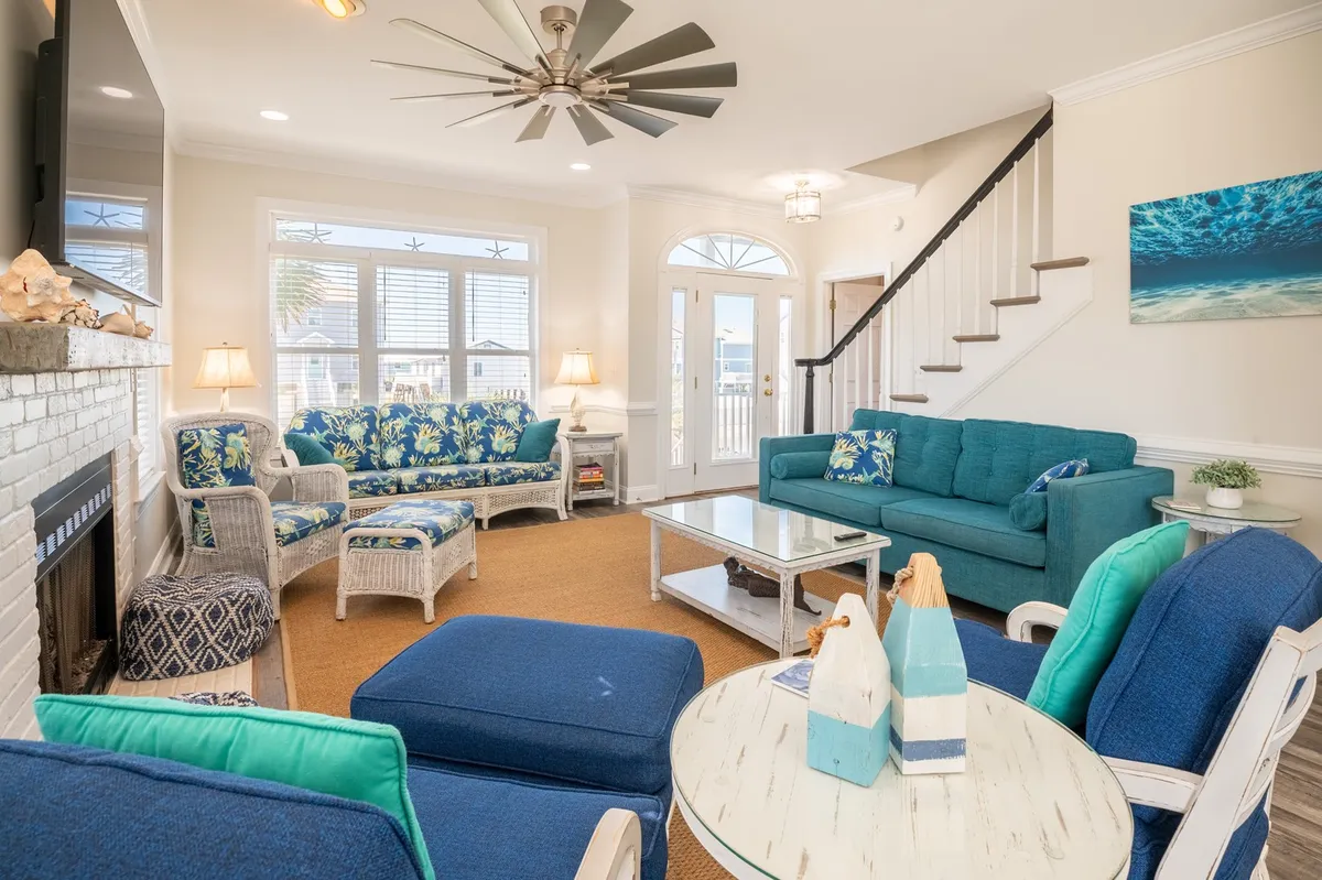 A bright, inviting living room with plush, colorful seating, a cozy fireplace, large windows, and stylish wall art. The arrangement is perfect for lively game nights or relaxed social gatherings.