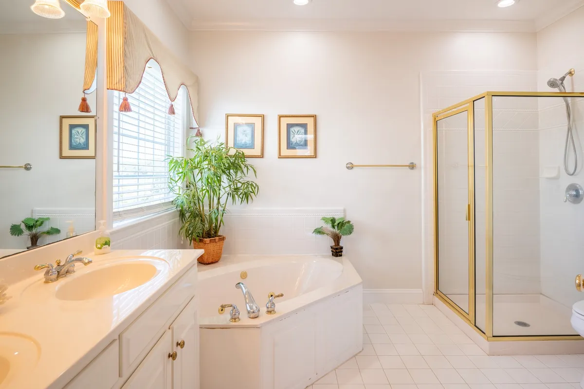 A tranquil bathroom scene with a bathtub, shower, plants, and framed artwork. The setting invites relaxation and quiet moments of self-care, perfectly embodying the spa-like promise of the home's multiple bathrooms.